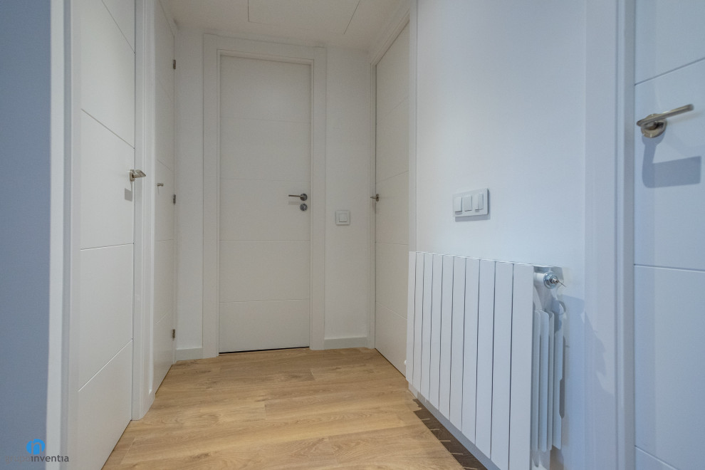 Idées déco pour un couloir contemporain de taille moyenne avec un mur blanc, un sol en bois brun et un sol marron.