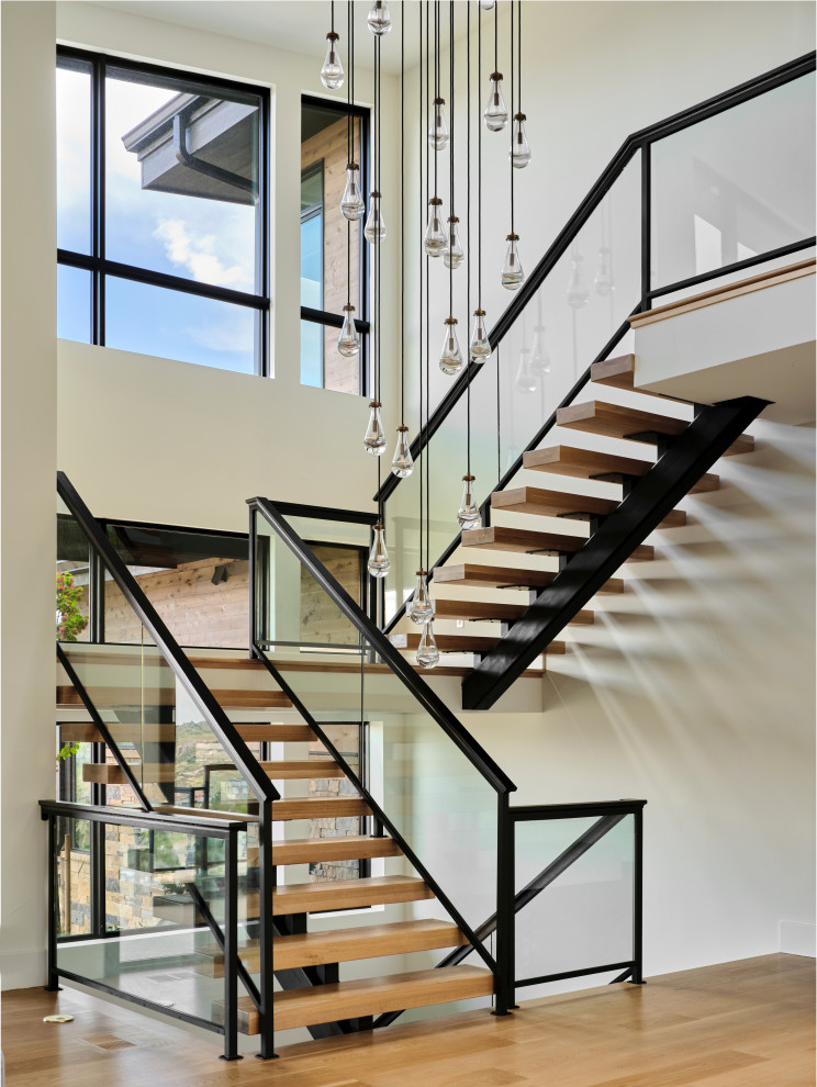 Свежая идея для дизайна: огромная п-образная деревянная лестница в современном стиле с деревянными ступенями и стеклянными перилами - отличное фото интерьера