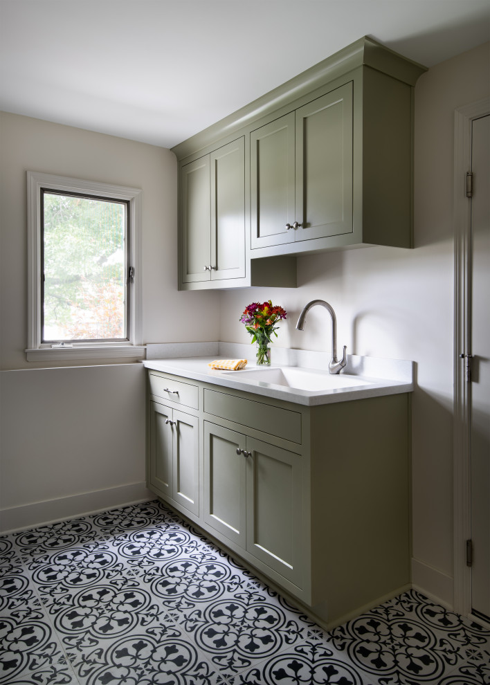 Inredning av en klassisk liten linjär tvättstuga enbart för tvätt, med en integrerad diskho, skåp i shakerstil, gröna skåp, bänkskiva i koppar, vita väggar, vinylgolv och flerfärgat golv