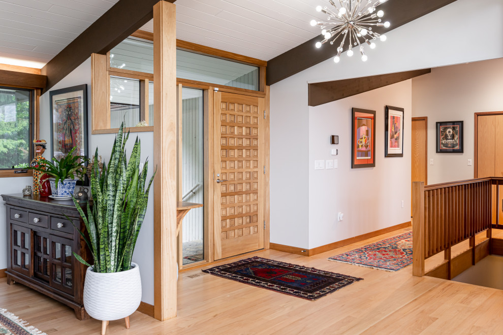 他の地域にある高級な中くらいなミッドセンチュリースタイルのおしゃれな玄関ロビー (グレーの壁、淡色無垢フローリング、淡色木目調のドア、ベージュの床、表し梁) の写真