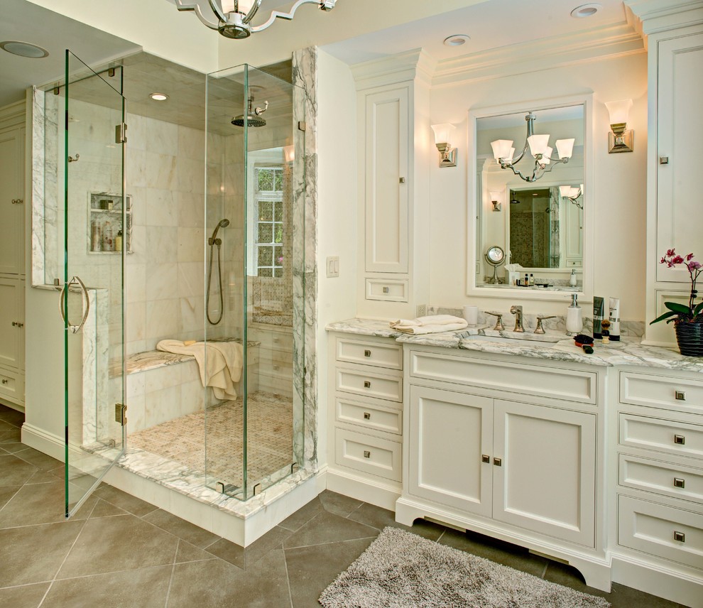 Design ideas for a large traditional master bathroom in New York with recessed-panel cabinets, white cabinets, a drop-in tub, beige walls, cement tiles, an undermount sink, marble benchtops, a corner shower, white tile, marble, grey floor and a hinged shower door.