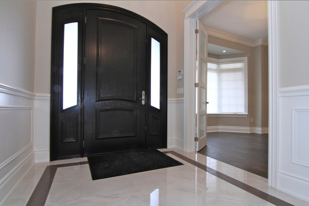 Photo of a mid-sized traditional foyer in Toronto with beige walls, marble floors, a single front door and a dark wood front door.