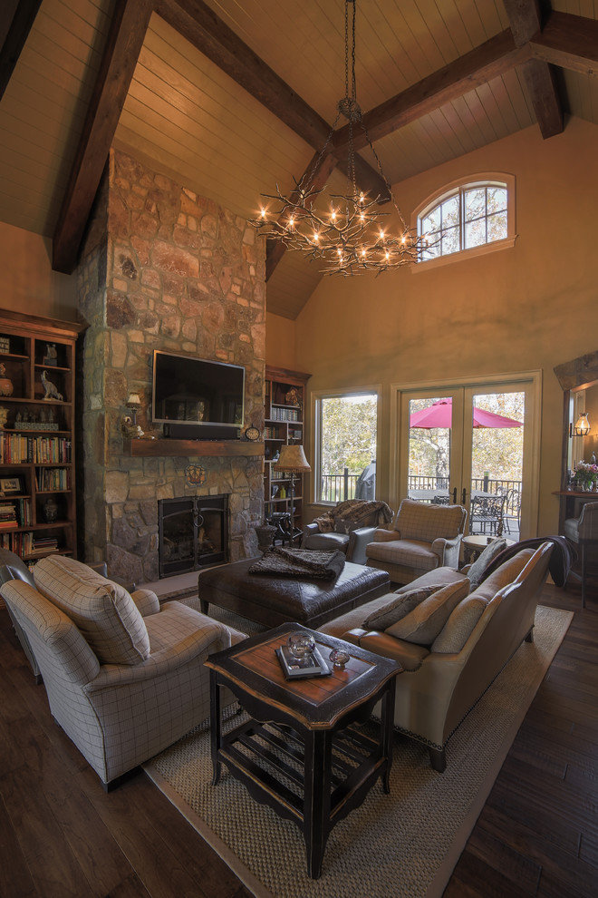 This is an example of a mid-sized country open concept family room in Charlotte with a home bar, yellow walls, dark hardwood floors, a standard fireplace, a stone fireplace surround and a wall-mounted tv.