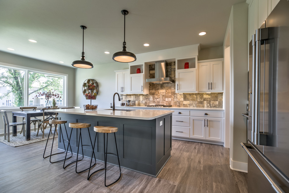 Inspiration for a transitional l-shaped medium tone wood floor and gray floor eat-in kitchen remodel in Omaha with an undermount sink, shaker cabinets, quartz countertops, stainless steel appliances, an island, white countertops, white cabinets, gray backsplash and subway tile backsplash
