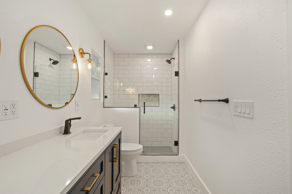 Example of a mid-sized trendy master ceramic tile, black floor and single-sink bathroom design in Austin with shaker cabinets, white cabinets, a two-piece toilet, white walls, an undermount sink, granite countertops, black countertops, a niche and a freestanding vanity