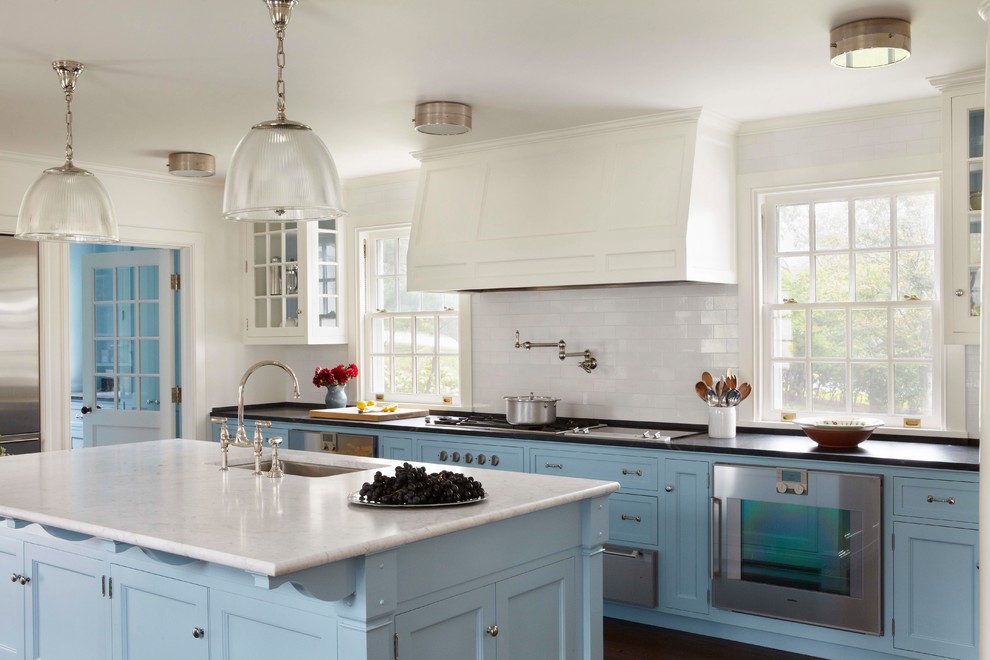 Photo of a beach style separate kitchen in Boston with an undermount sink, recessed-panel cabinets, blue cabinets, white splashback, subway tile splashback, stainless steel appliances, dark hardwood floors, with island, brown floor, marble benchtops and white benchtop.