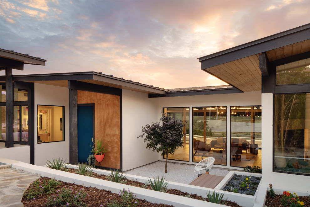 Inspiration for a large midcentury one-storey stucco white house exterior in Austin with a metal roof and a black roof.