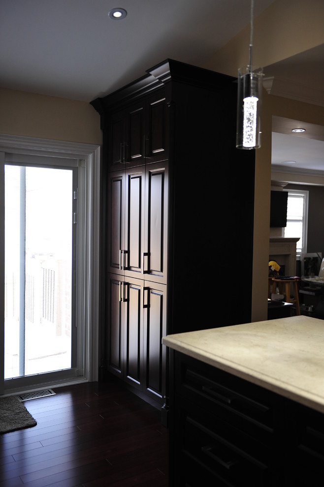 Example of a mid-sized transitional u-shaped eat-in kitchen design in Toronto with a double-bowl sink, raised-panel cabinets, dark wood cabinets, quartz countertops, multicolored backsplash, matchstick tile backsplash, stainless steel appliances and a peninsula