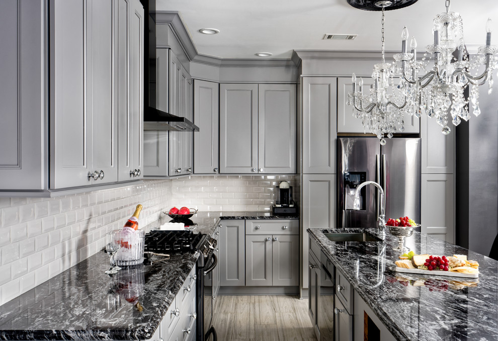 Transitional l-shaped ceramic tile and gray floor eat-in kitchen photo in Other with an undermount sink, granite countertops, stainless steel appliances, an island, gray cabinets, white backsplash, black countertops, recessed-panel cabinets and subway tile backsplash