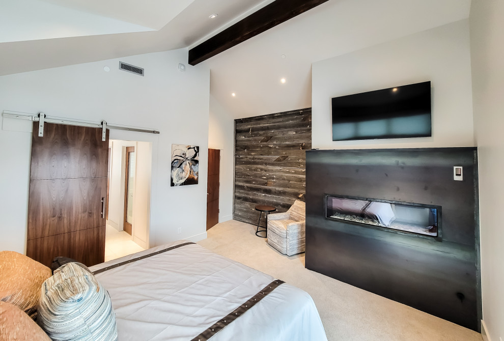 Пример оригинального дизайна: большая хозяйская спальня в современном стиле с белыми стенами, ковровым покрытием, горизонтальным камином, фасадом камина из металла, бежевым полом, сводчатым потолком и деревянными стенами
