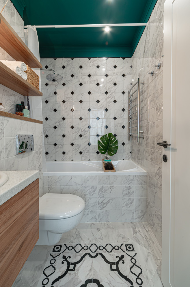 Inredning av ett minimalistiskt litet vit vitt en-suite badrum, med släta luckor, skåp i mellenmörkt trä, ett undermonterat badkar, en vägghängd toalettstol, svart och vit kakel, keramikplattor, klinkergolv i keramik, ett nedsänkt handfat, bänkskiva i akrylsten och dusch med duschdraperi