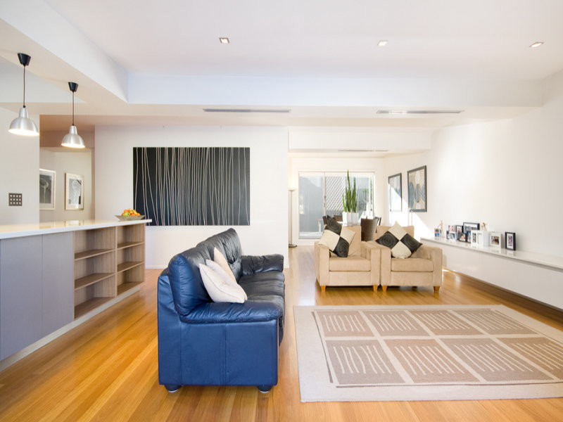 Large contemporary open concept family room in Sydney with white walls, light hardwood floors and a wall-mounted tv.