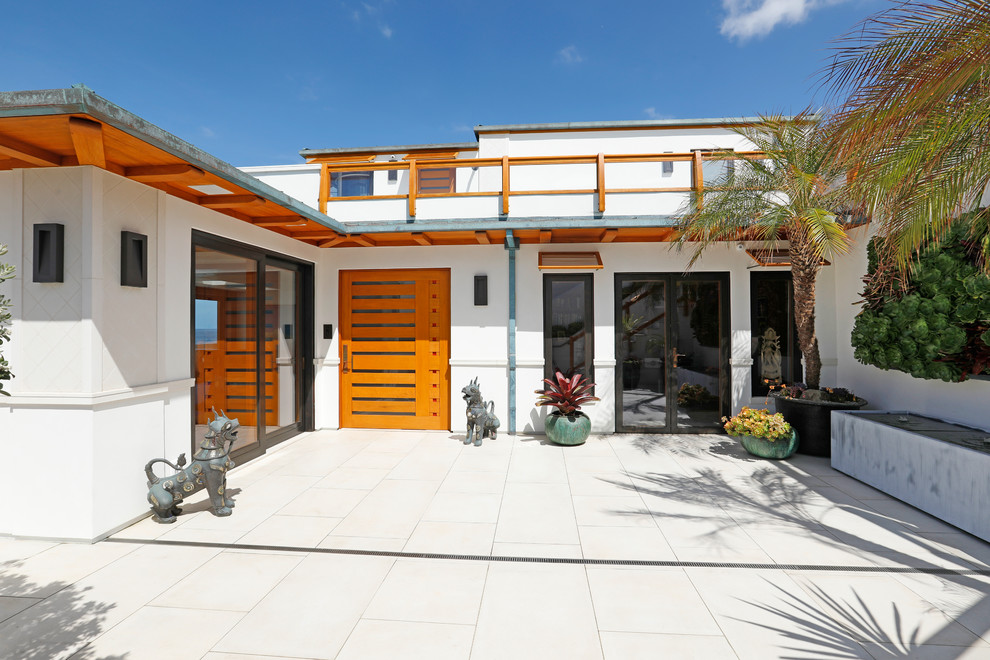 Large beach style split-level stucco white house exterior in Orange County with a metal roof.