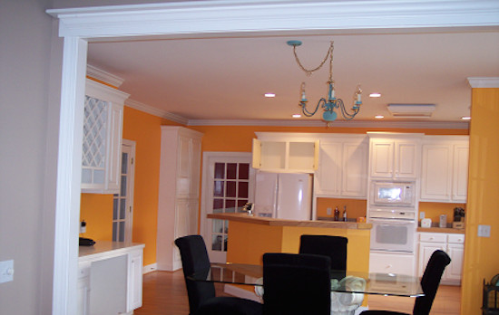 Eat-in kitchen - single-wall light wood floor eat-in kitchen idea with raised-panel cabinets, white cabinets, yellow backsplash, white appliances and an island