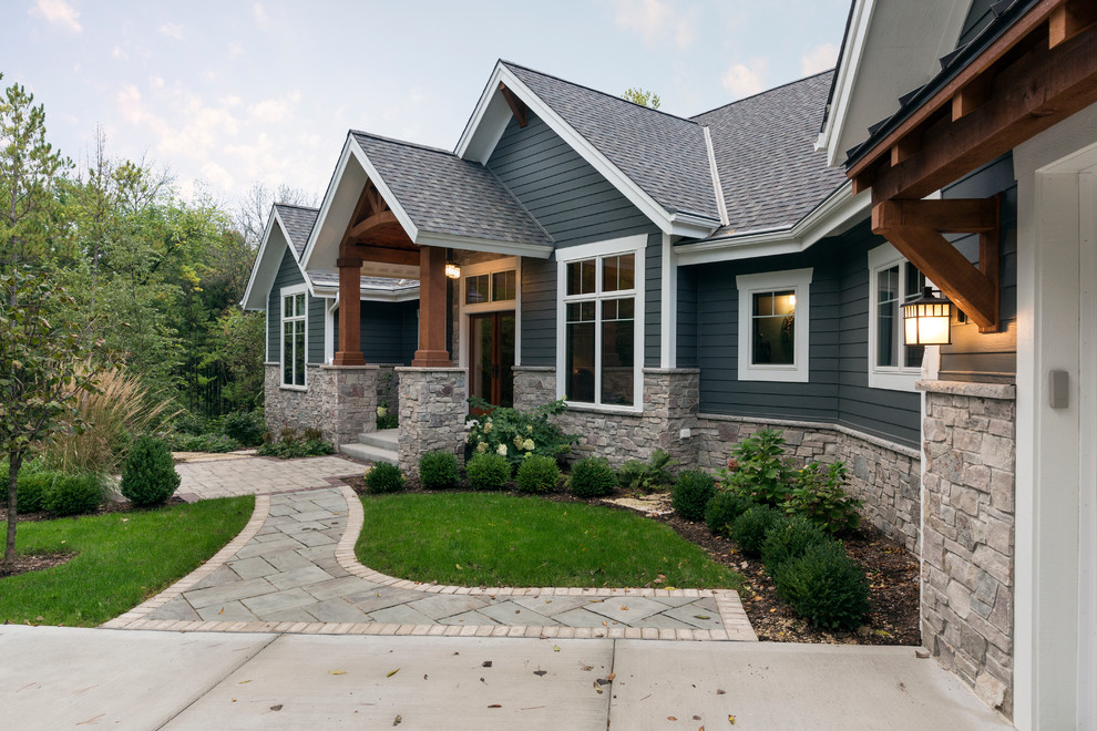 This is an example of a large arts and crafts one-storey concrete blue house exterior in Milwaukee with a gable roof and a shingle roof.