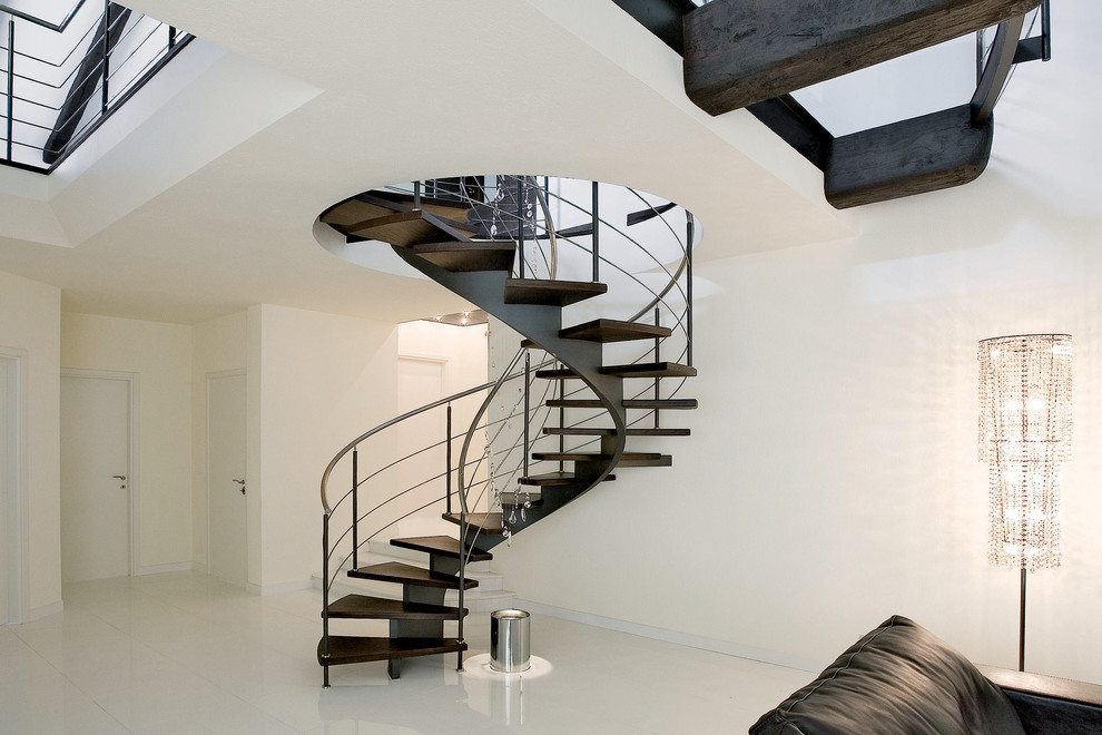 Contemporary wood spiral staircase in Turin with open risers and metal railing.