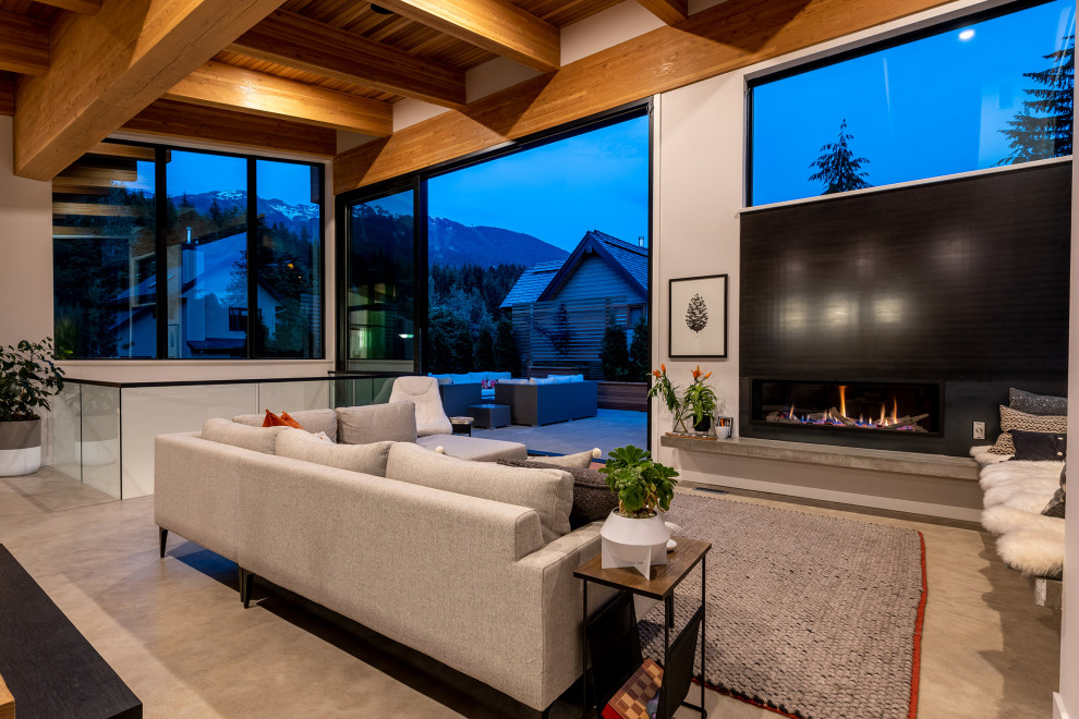 This is an example of a large contemporary open concept living room in Vancouver with white walls, concrete floors, a standard fireplace, black floor and exposed beam.