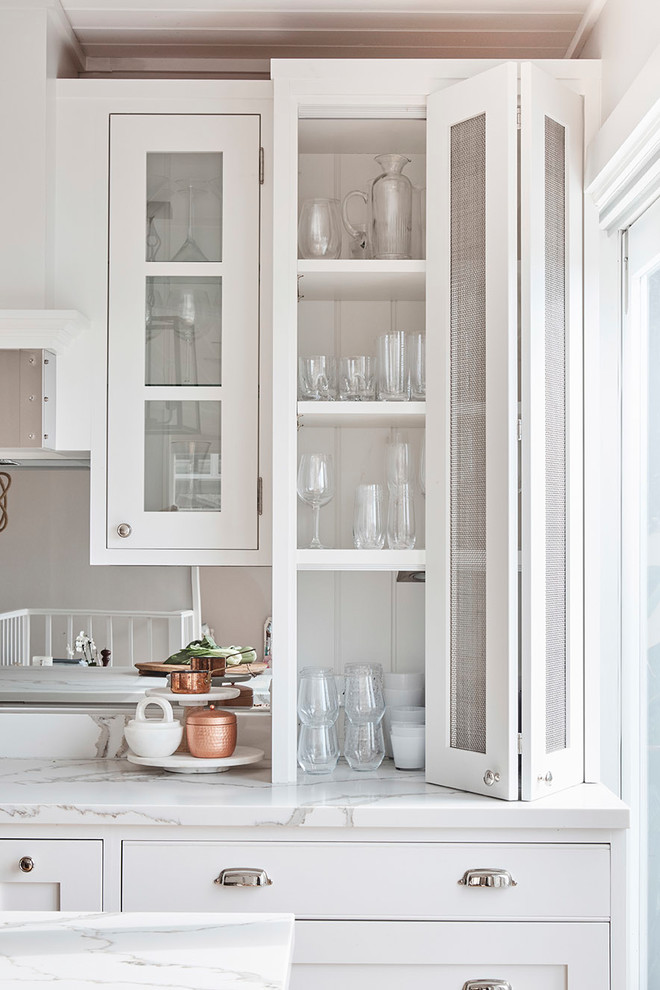 Mid-sized country u-shaped kitchen pantry in Sydney with a farmhouse sink, shaker cabinets, white cabinets, marble benchtops, white splashback, subway tile splashback, stainless steel appliances, light hardwood floors and with island.