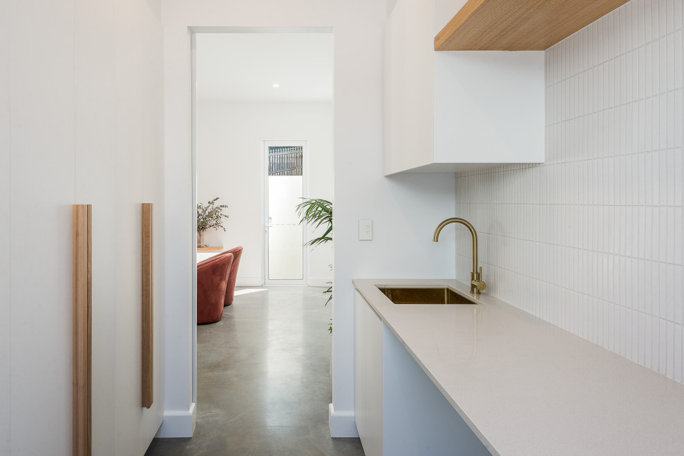 Design ideas for a large contemporary utility room in Brisbane with white splashback and concrete flooring.