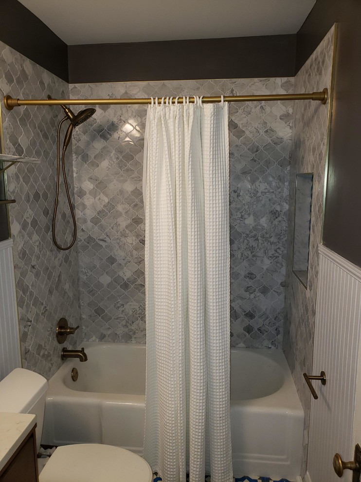 This is an example of a small contemporary bathroom in Raleigh with brown cabinets, an alcove tub, a shower/bathtub combo, a two-piece toilet, blue tile, white tile, marble, grey walls, mosaic tile floors, quartzite benchtops, multi-coloured floor, a shower curtain and white benchtops.