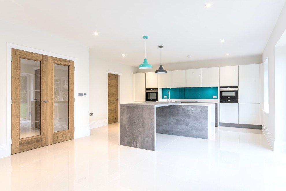 Inspiration for a medium sized contemporary kitchen in Berkshire with a built-in sink, flat-panel cabinets, white cabinets, laminate countertops, blue splashback, glass tiled splashback, integrated appliances and an island.