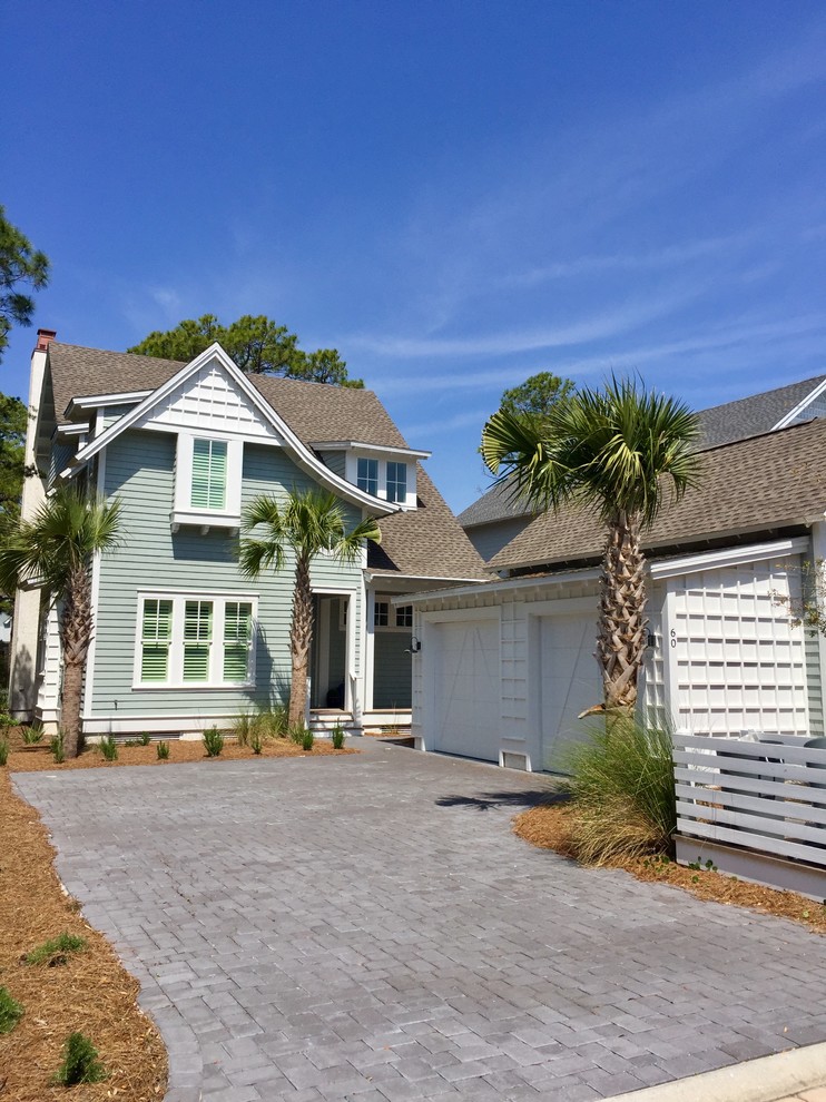 This is an example of a mid-sized beach style two-storey green house exterior in Austin with wood siding, a gable roof and a shingle roof.
