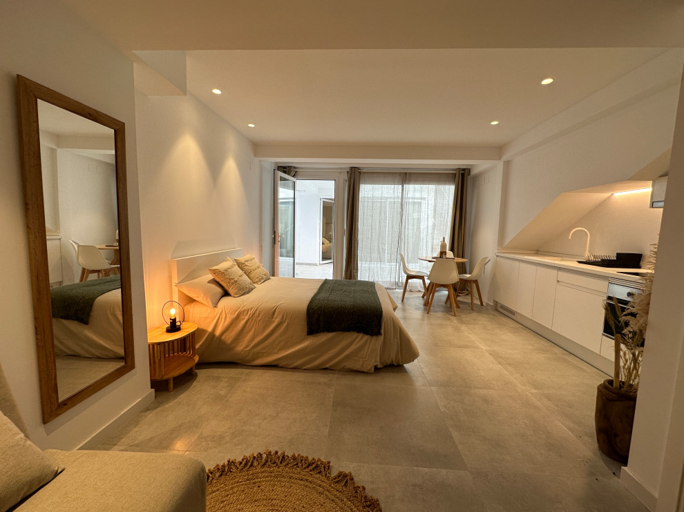 Diseño de dormitorio tipo loft y gris y blanco mediterráneo con paredes blancas y suelo gris