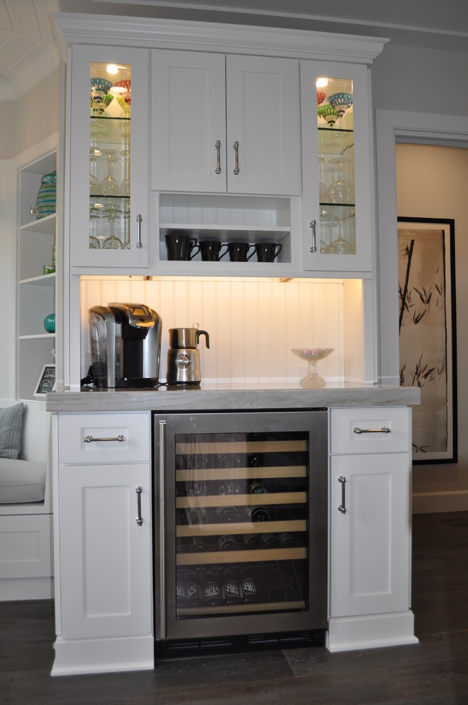 Inspiration for a small traditional home bar in Los Angeles with recessed-panel cabinets, white cabinets, quartzite benchtops, grey splashback, dark hardwood floors and no sink.