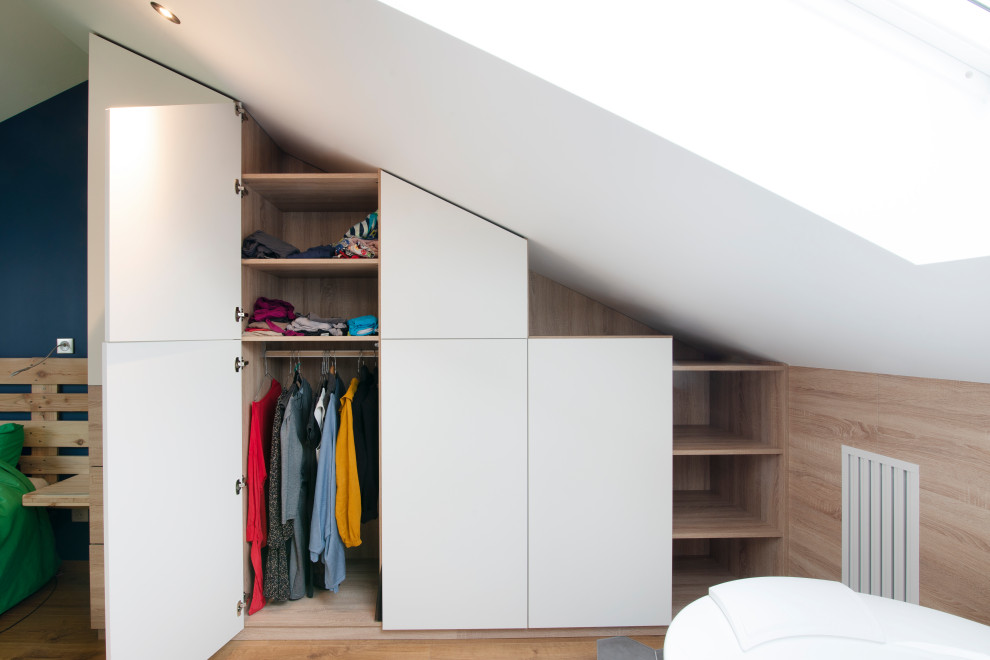 This is an example of a large contemporary gender-neutral built-in wardrobe in Nancy with laminate floors, brown floor, flat-panel cabinets and white cabinets.