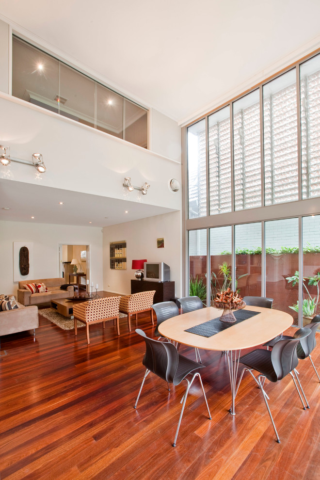 This is an example of a contemporary open plan dining in Sydney with white walls and medium hardwood floors.