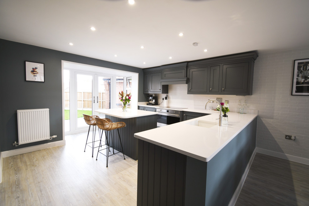 Inspiration for a large traditional l-shaped eat-in kitchen in Essex with a single-bowl sink, shaker cabinets, grey cabinets, quartzite benchtops, black appliances, with island and white benchtop.