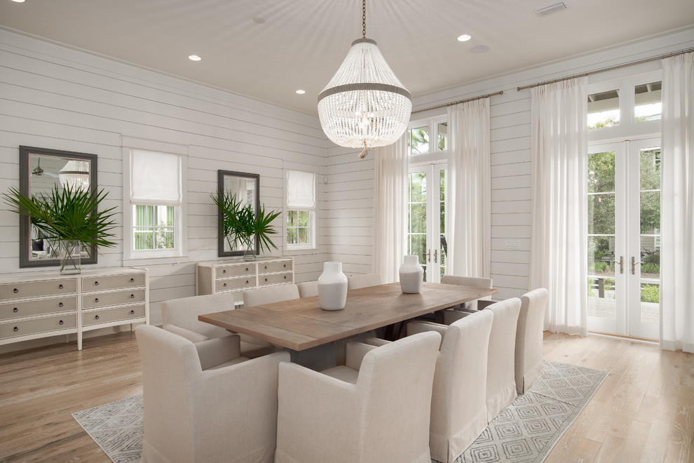 This is an example of a beach style dining room with white walls, light hardwood floors, no fireplace and beige floor.