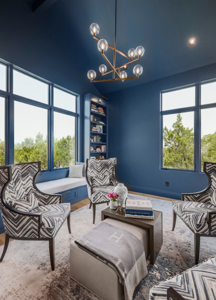 This is an example of a transitional home office in Austin with a library, blue walls and vaulted.