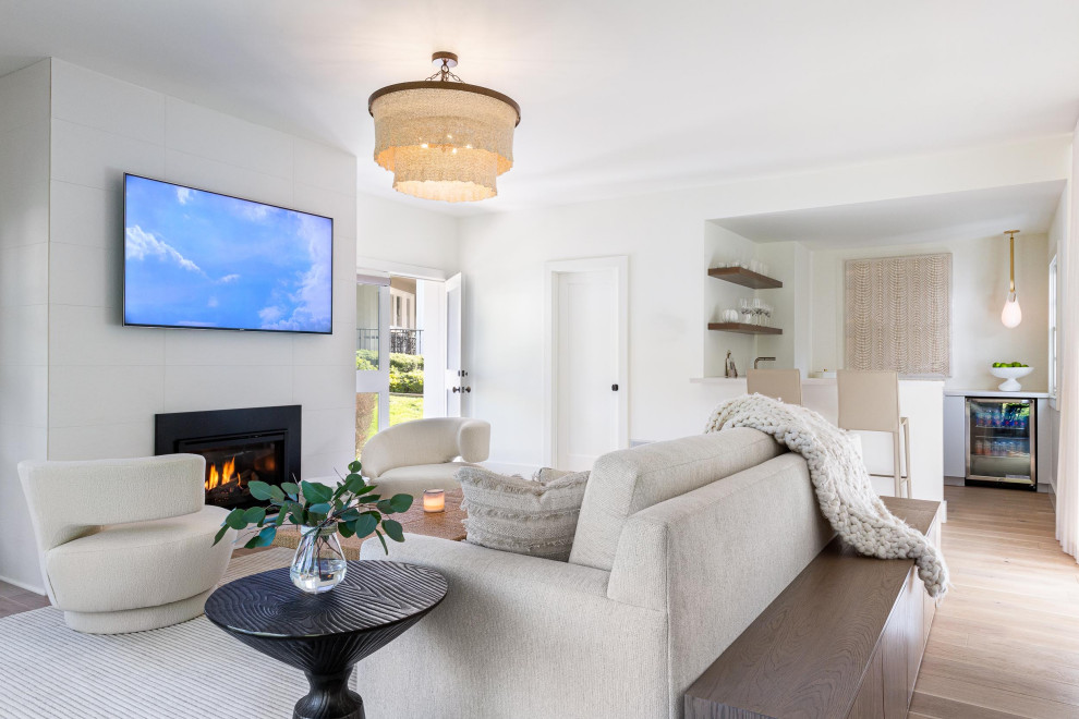 Beach style living room in San Francisco with white walls, medium hardwood floors, a hanging fireplace, a tile fireplace surround and a wall-mounted tv.