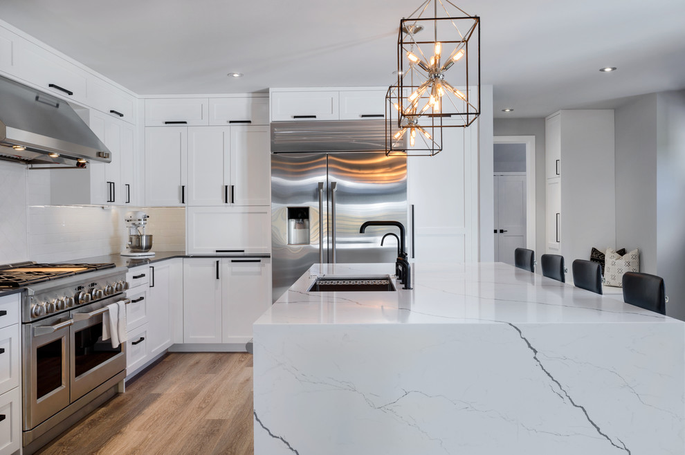 Mid-sized transitional eat-in kitchen in Seattle with an undermount sink, shaker cabinets, white cabinets, quartz benchtops, white splashback, subway tile splashback, stainless steel appliances, vinyl floors, with island, beige floor and white benchtop.