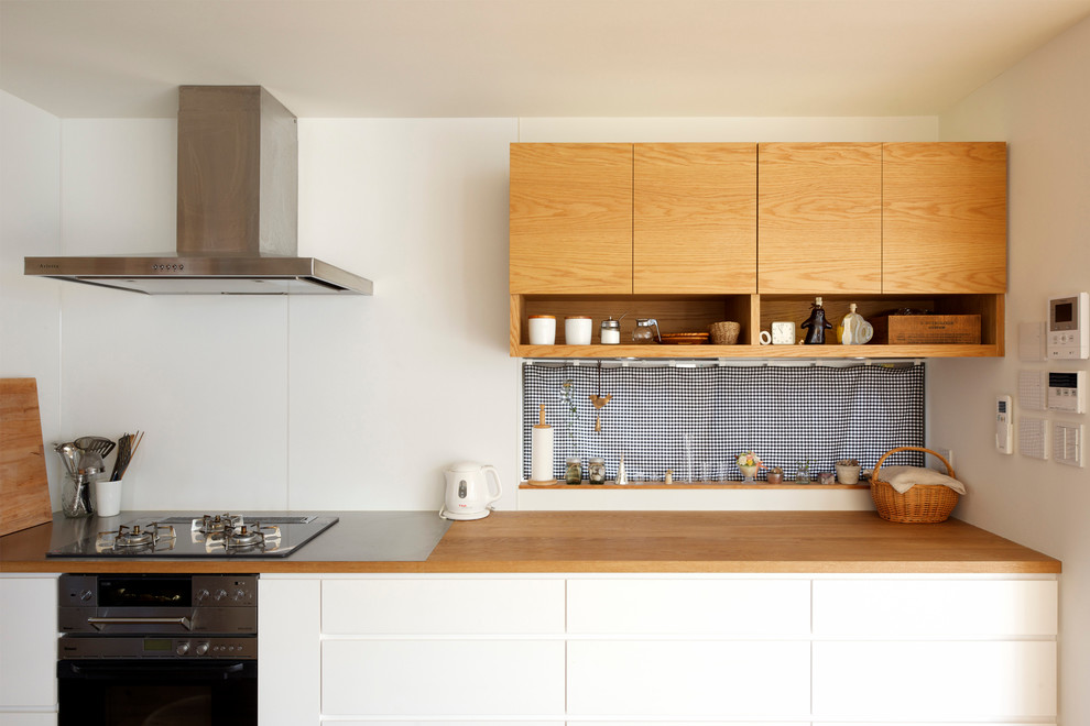 This is an example of a contemporary single-wall kitchen in Other with flat-panel cabinets, white cabinets, wood benchtops and white splashback.