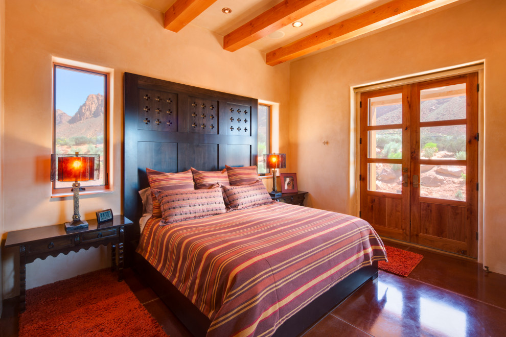 На фото: спальня в стиле фьюжн с оранжевыми стенами, бетонным полом, красным полом и балками на потолке с