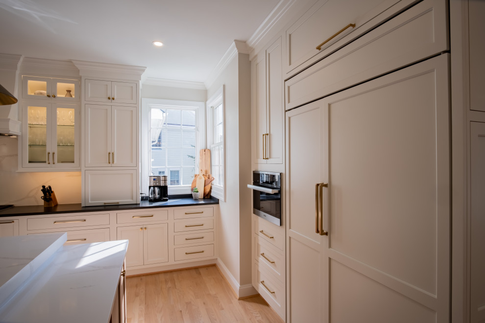 This is an example of a large traditional l-shaped eat-in kitchen in DC Metro with an undermount sink, beaded inset cabinets, white cabinets, quartz benchtops, white splashback, engineered quartz splashback, stainless steel appliances, light hardwood floors, with island, brown floor, white benchtop and wallpaper.