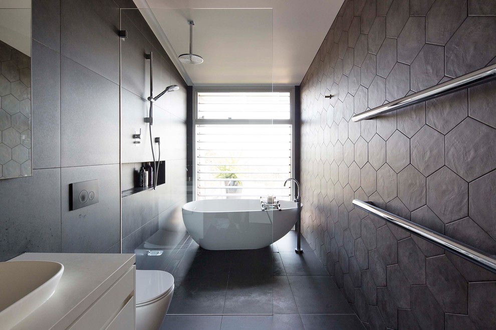 This is an example of a large contemporary master bathroom in Sydney with a freestanding tub, an open shower, grey walls, ceramic floors, grey floor and an open shower.