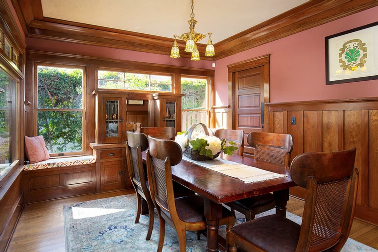 Cette photo montre une salle à manger craftsman fermée et de taille moyenne avec un mur rouge, un sol en bois brun, un sol marron, un plafond décaissé et boiseries.