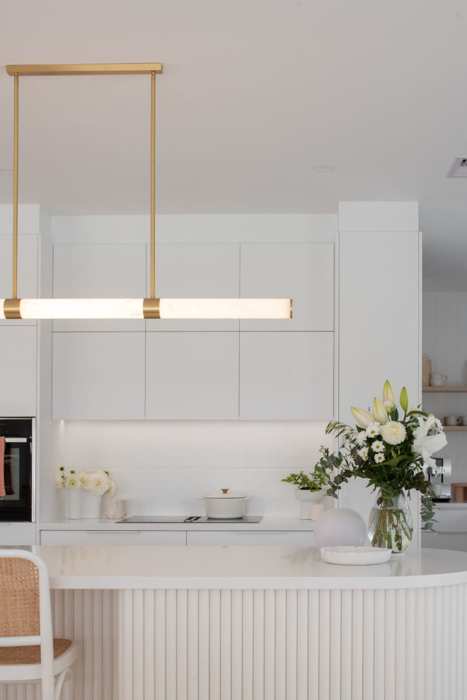 Photo of a country open plan kitchen in Hobart with an undermount sink, white cabinets, quartz benchtops, white splashback, with island, white floor and white benchtop.