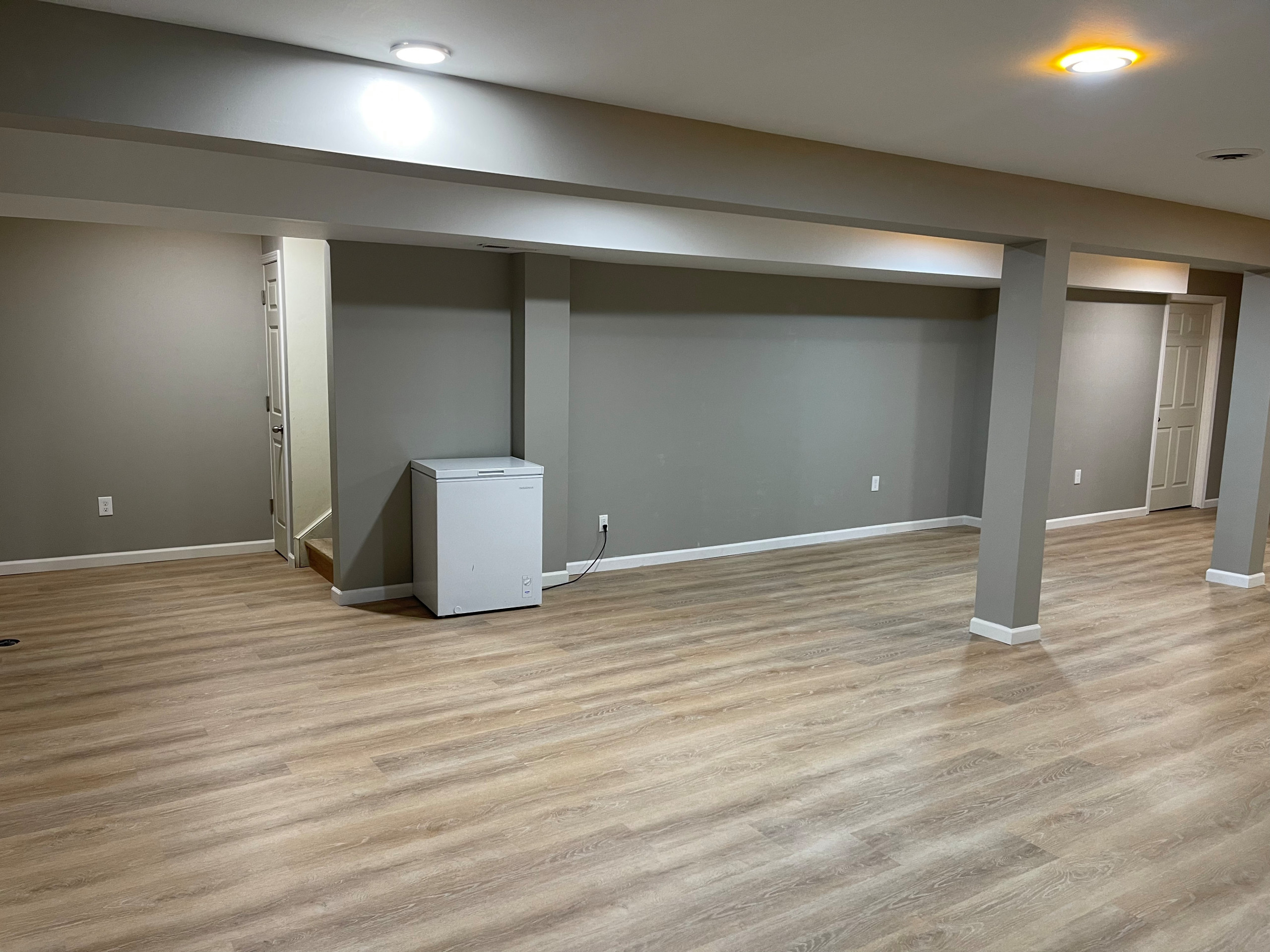 Inspiration for a large modern underground vinyl floor and brown floor basement remodel in Cleveland with gray walls and no fireplace