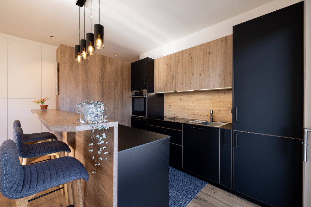 Foto på ett mellanstort funkis svart kök, med en enkel diskho, släta luckor, svarta skåp, bänkskiva i koppar, beige stänkskydd, rostfria vitvaror, mellanmörkt trägolv och brunt golv