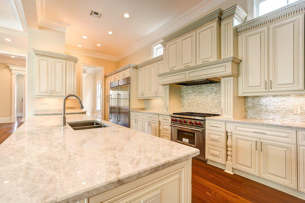Inspiration for an expansive transitional galley eat-in kitchen in New Orleans with an undermount sink, beaded inset cabinets, beige cabinets, quartzite benchtops, stainless steel appliances, medium hardwood floors, multiple islands, beige splashback, mosaic tile splashback and brown floor.