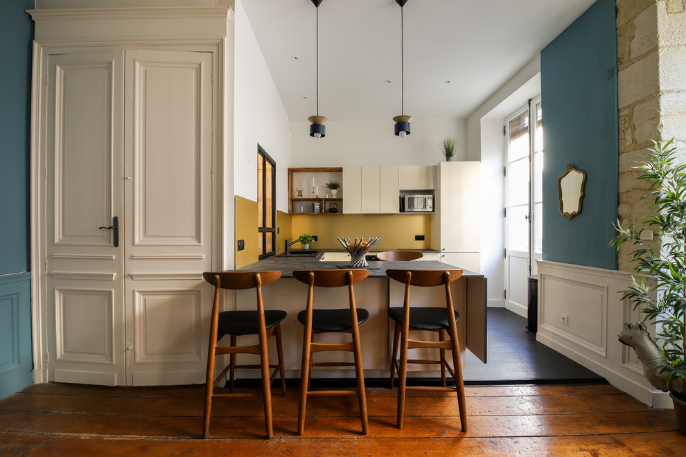 Inspiration for a small eclectic u-shaped eat-in kitchen in Bordeaux with a single-bowl sink, beige cabinets, laminate benchtops, yellow splashback, black appliances, laminate floors, with island, black floor and black benchtop.