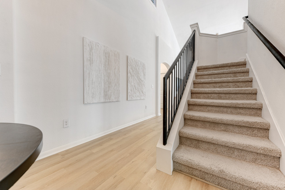 This is an example of a mid-sized transitional carpeted u-shaped staircase in Austin with concrete risers and metal railing.