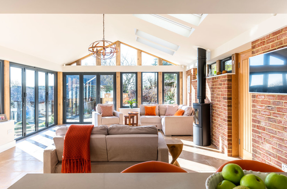 Large contemporary sunroom in Buckinghamshire with a wood stove, a skylight and beige floor.