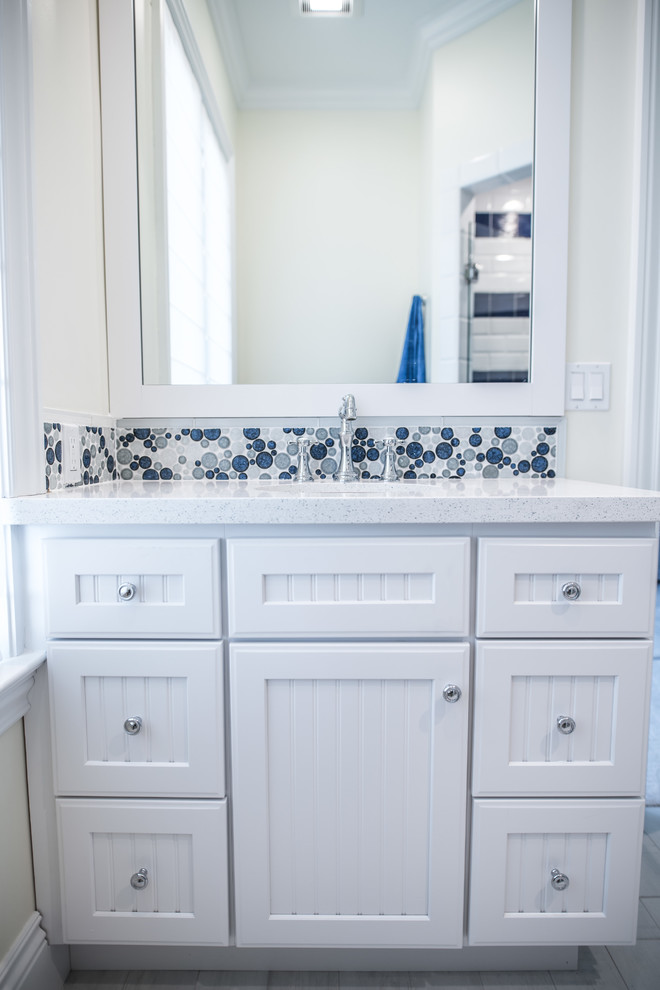 Mid-sized beach style 3/4 bathroom in Miami with shaker cabinets, white cabinets, a corner shower, a one-piece toilet, white walls, porcelain floors, an undermount sink and solid surface benchtops.