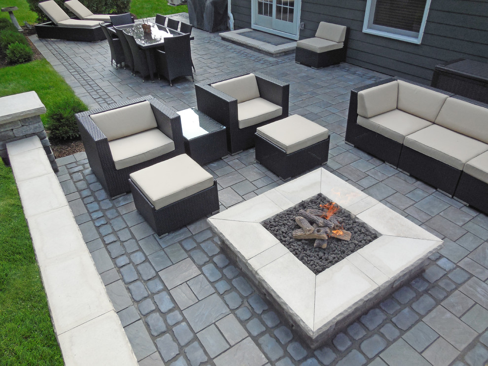This is an example of a large contemporary backyard patio in Detroit with a fire feature, concrete pavers and no cover.