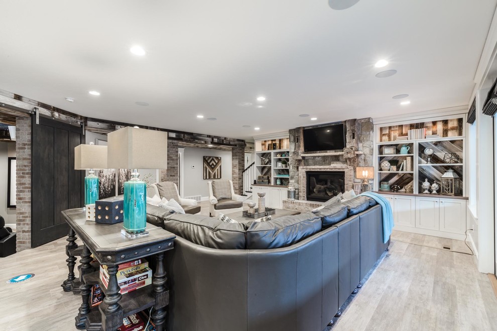 This is an example of an expansive transitional walk-out basement in Salt Lake City with grey walls, medium hardwood floors, a standard fireplace, a brick fireplace surround and grey floor.